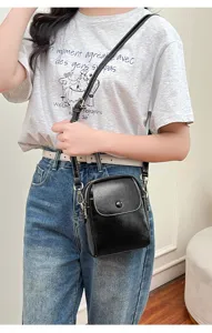 Detailed view of the stylish black crossbody bag showing its button flap and compact design.