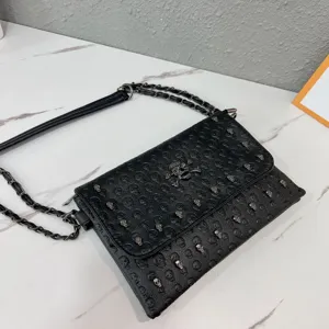 Close-up detail of the black leather punk style skull embossed chain envelope bag.