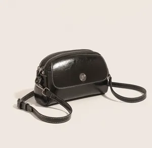 Detailed view of black oil wax leather shell crossbody bag, featuring multi-compartment design.