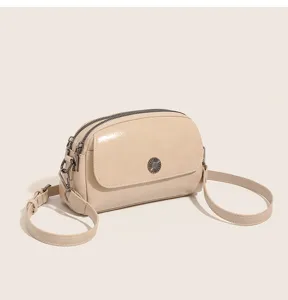Detail view of oil wax leather crossbody shell bag with double zipper and metal button.