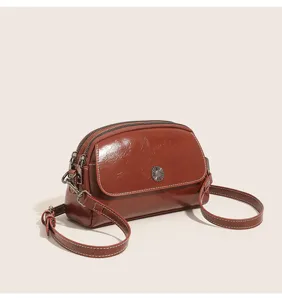 Close-up detail of retro oil-wax leather women's shoulder bag with multi-compartments.