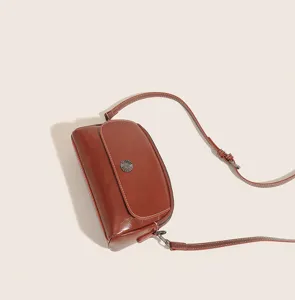 Vintage brown oil wax leather crossbody bag with retro metal concho button and contrast stitching.