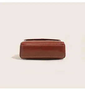 Brown oil wax leather handbag bottom detail shot showing neat white stitching and fine texture.