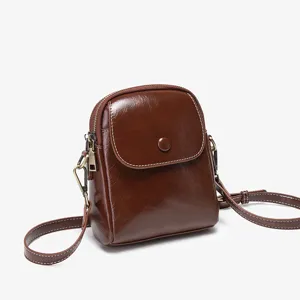 Brown patent leather small crossbody bag with flap, button closure and contrast stitching.