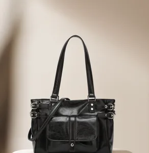 Black PU leather tote bag detail showing metal buckles, front pocket and sturdy double straps.