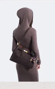 Back view detail of brown suede shoulder bag with metal turn-lock closure and dog charm.