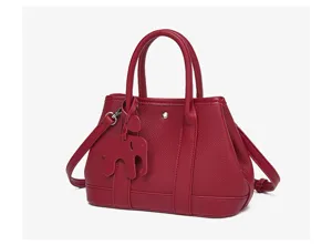 Detail shot of red leather tote bag featuring elegant double handles and cute elephant charm.