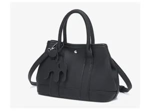 Black leather tote bag detail showcasing pebble texture, sturdy handles, and cute elephant charm.