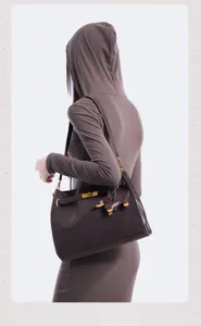 Retro brown suede shoulder bag with chic lock closure and cute dachshund charm for women.