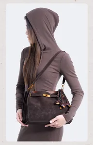 Detail view of vintage brown suede shoulder bag with metal turn-lock and cute animal charm.