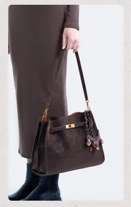 Detail shot of retro brown suede shoulder bag with metallic lock closure and cute charm.