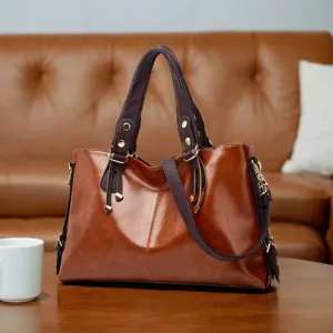 Detail view of brown leather handbag, contrasting dark handles on wooden table in cozy room.