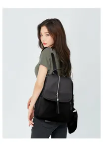 Detail shot of a black oxford cloth backpack with tassel zipper on a model for travel.