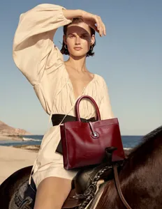 Detailed view of dark red leather commuter handbag, featuring elegant top handles and lock detail.