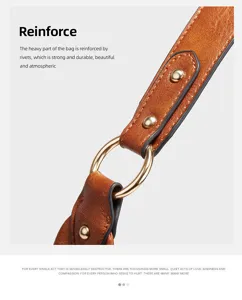 Close-up detail of vintage brown leather handbag strap with metal ring and metal rivets reinforcement.