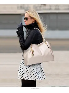 Detail shot of a stylish large capacity shoulder tote bag in elegant beige leather with gold hardware.