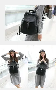 Detail shot of the black soft leather backpack worn by a model in a modern indoor setting.