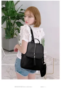 Detail view of stylish black nylon backpack featuring front tassel zipper and spacious design.