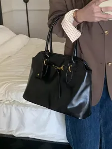 Detailed view of a retro black leather tote bag with elegant metal hardware. Stylish look.