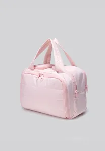 Pink quilted cosmetic bag detail showing durable zipper and handle design for travel.