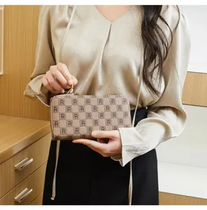 Brown checkered monogram pattern clutch wallet detail view featuring elegant gold zipper hardware.