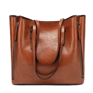 Close-up detail of the brown oil leather tote handbag, showing texture and side zipper design.