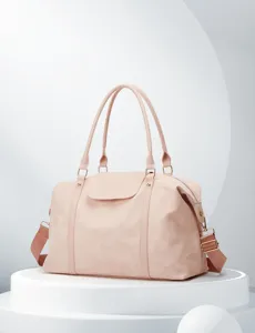 Detalle de bolso de viaje rosa con cuero liso, herrajes dorados y asas resistentes.