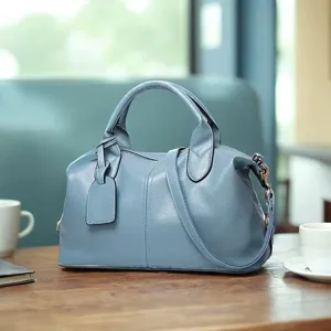 Blue leather Boston handbag detail showcasing texture and hardware in cafe scene.