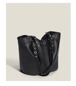 Detailed view of black leather bucket bag featuring stylish grommet studded straps design.