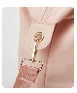 Primer plano de la correa de la bolsa de viaje rosa con herrajes dorados y cinta.