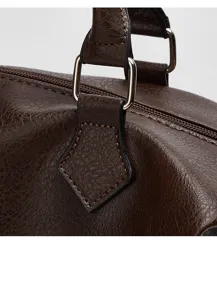 Brown leather bag detail showing texture, metal hardware, and sturdy handle attachment craftsmanship.