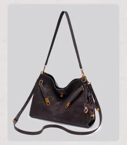 Close-up of dark brown suede shoulder bag with chic metal lock clasp and cute dog charm.