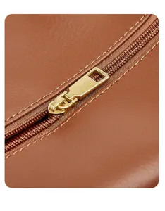 Close-up detail of women's brown leather bag with golden metal zipper and neat stitching.