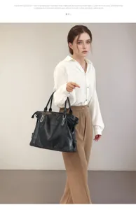 Detail view of black leather tote bag, showing large capacity, durable handles and hardware.