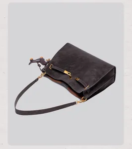 Retro suede shoulder bag with metal lock and decorative straps, elegant dark grey handbag.