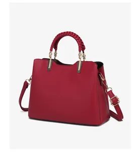 Red leather handbag detail showcasing braided handle texture and metallic hardware links.