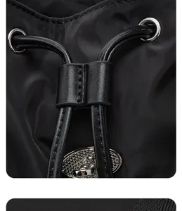 Detail view of black nylon backpack featuring metal hardware, secure drawstring, and lock plate.