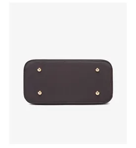 Detailed bottom view of dark brown leather handbag featuring four gold metal feet.