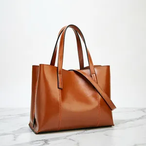 Brown oil wax leather tote bag closeup, vintage handbag detail, premium textured shoulder bag.
