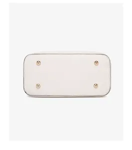 Detailed bottom view of white leather handbag with four gold metal protective feet.