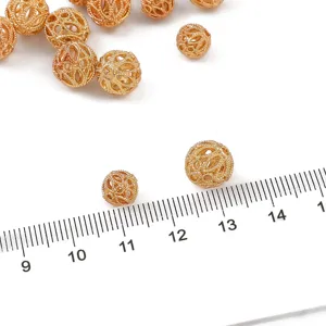 Détail macro de perles intercalaires dorées filigranées montrant la texture et la taille