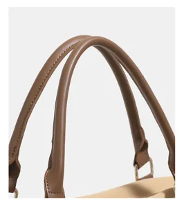Close-up detail view of the brown leather handbag handle with neat stitching and hardware.