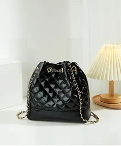 Detailed view of black patent quilted bucket bag with luxury gold chain and drawstring.