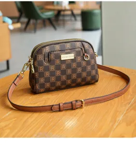 Brown patterned shell crossbody bag detail showing classic monogram print and metal hardware.
