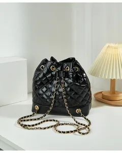 Close-up detail view of a black quilted leather bucket bag with elegant gold chain strap.