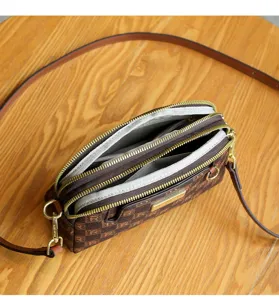Detailed view of the multi-zipper brown printed crossbody shoulder bag showing interior storage.