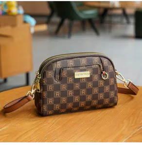 Stylish brown checkered crossbody shell bag with double zippers and metal plaque detail.