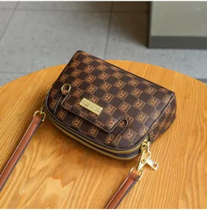 Detailed view of the brown patterned crossbody shoulder bag with double zipper and metal logo.