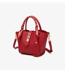 Red leather bucket bag with top handle and scarf accessory, stylish minimalist design.
