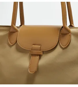 Close-up detail of the durable nylon tote handbag featuring a classic leather flap and sturdy handles.